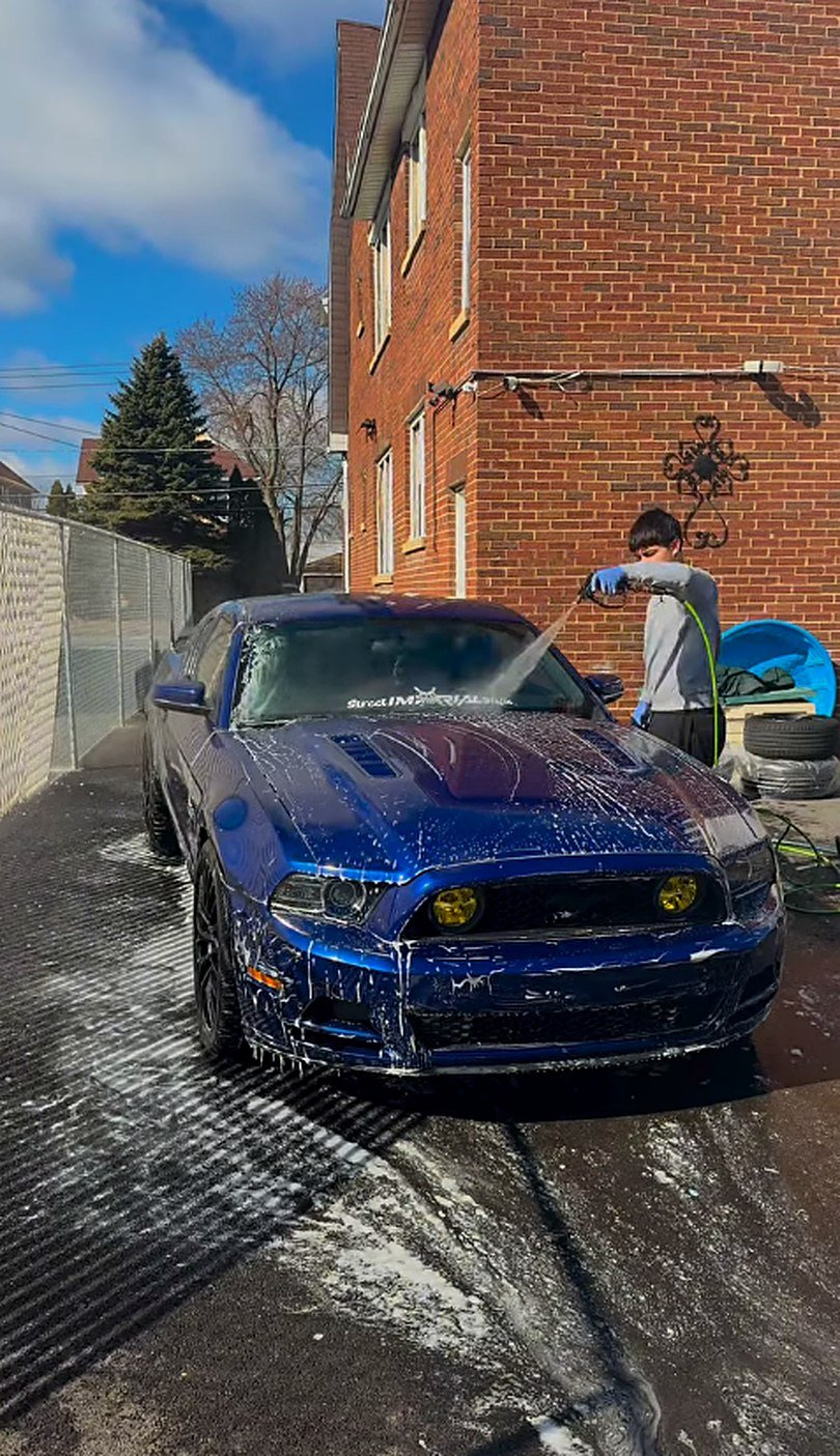 Blue Mustang covered in foam being rinsed